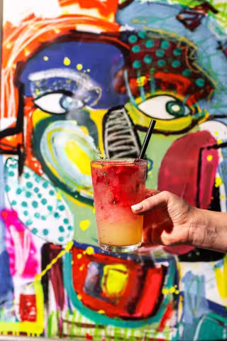 Signature cocktail in front of the graffiti art wall at Backyard Smokehouse Mississauga