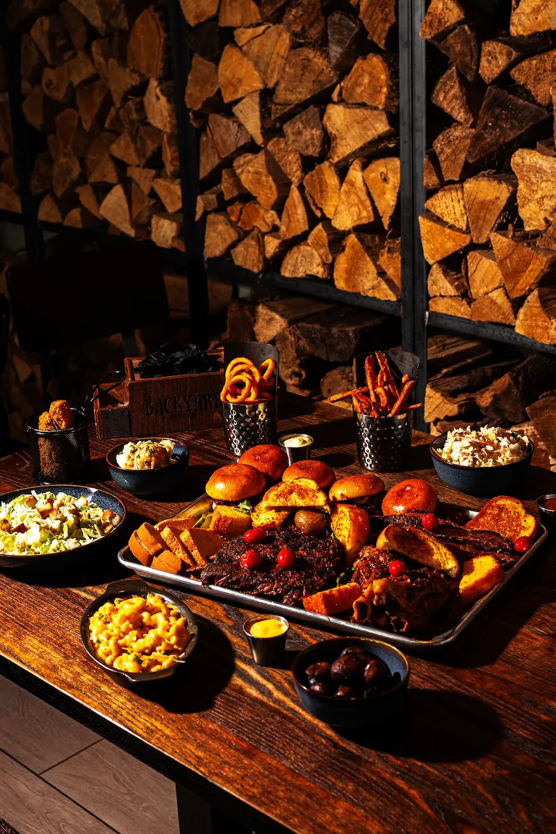 Backyard Smokehouse Edmonton pulled brisket sliders with cornbread on dark slate board under warm light