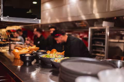 Backyard Smokehouse Edmonton kitchen chefs plating salads and bread at the pass during service